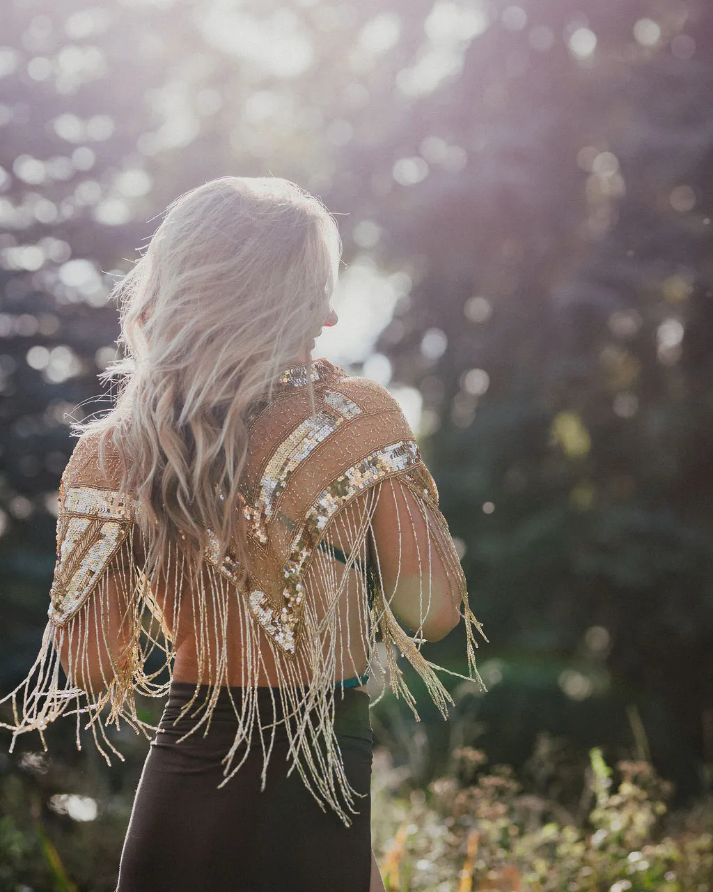 Taylor Tatum seen from behind in a sunlit gold sequin fringe Edge of Ether cape