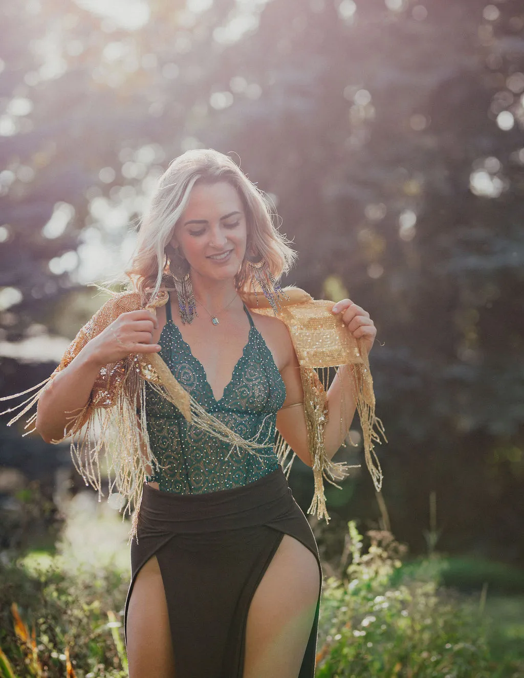 Taylor Tatum outdoors in warm sunlight, wrapped in a gold fringe shawl
