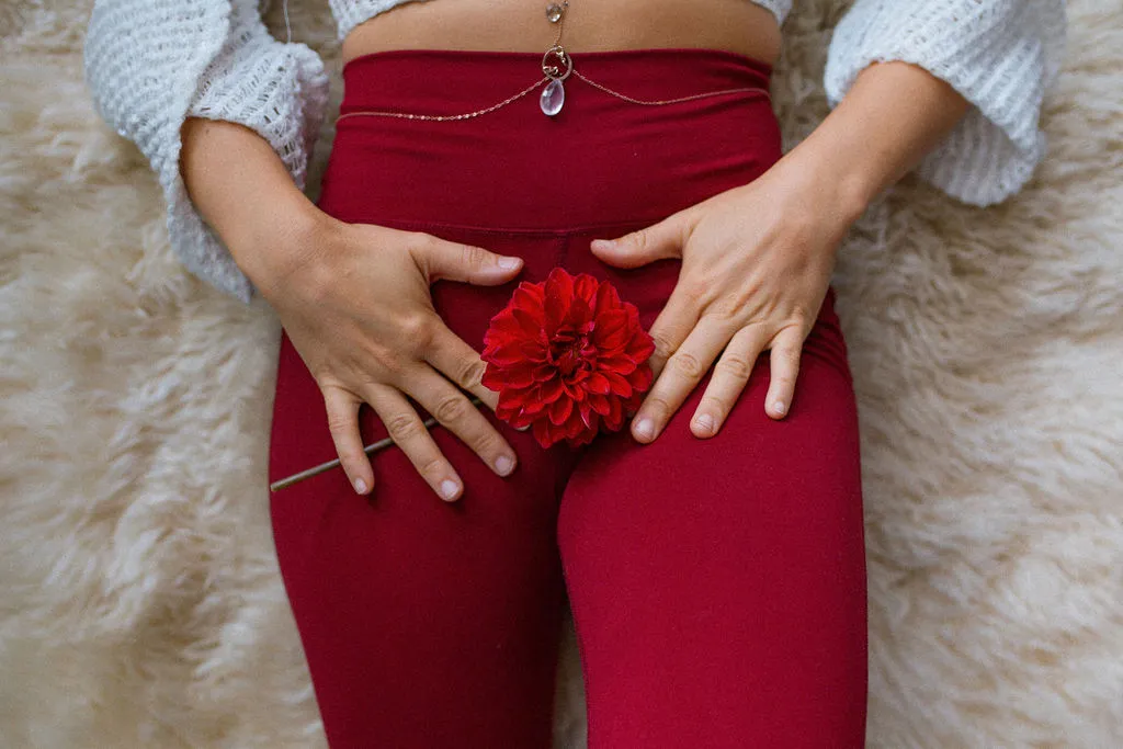 Legs in red leggings resting on a sheepskin beside a red dahlia
